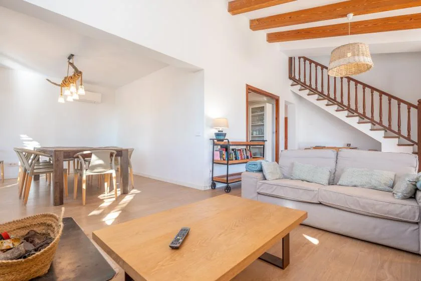 Una luminosa sala de estar y comedor con sofá, mesa de comedor y escalera.