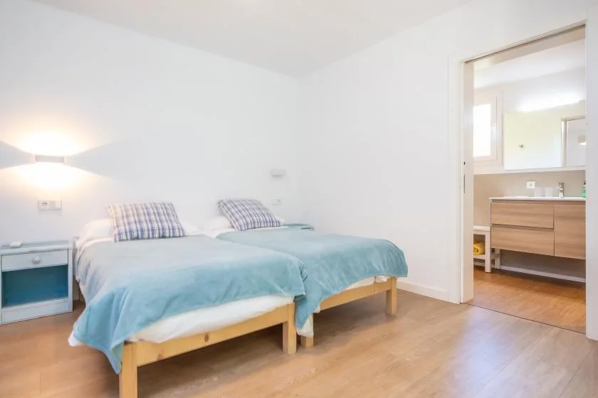 Un dormitorio con dos camas vestidas con ropa de cama azul y una puerta abierta a una zona de tocador.