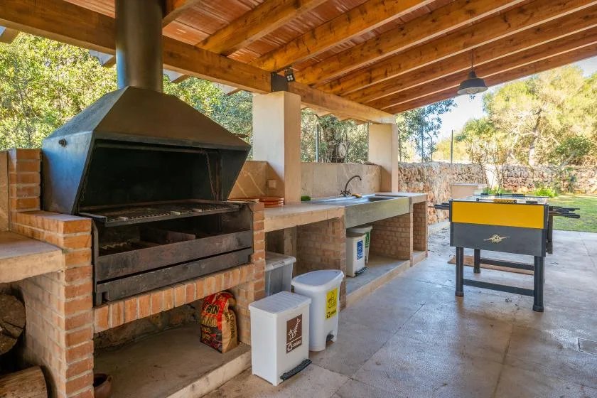 Una zona de cocina exterior cubierta con una parrilla grande y un fregadero.