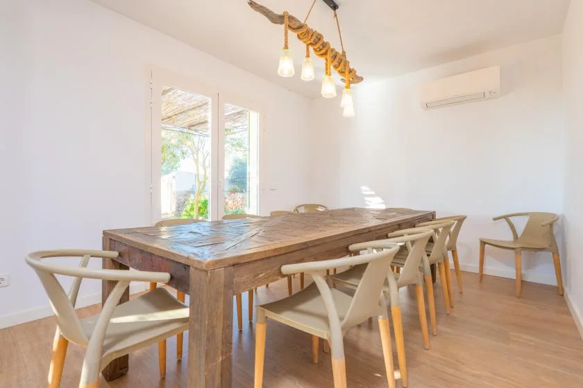 Un comedor luminoso con una mesa larga de madera y sillas.