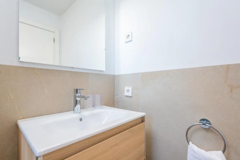 Un lavabo de baño con un armario con espejo y un aro para toalla.