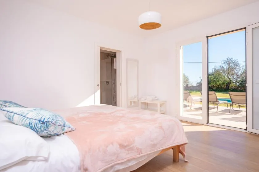 Un dormitorio luminoso con una cama junto a puertas corredizas de vidrio que dan a un patio.