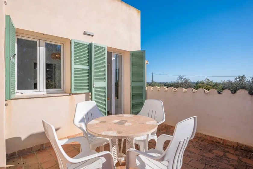 Una terraza soleada con una mesa redonda y asientos al aire libre.