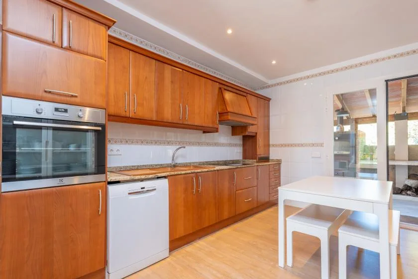 Una cocina luminosa con gabinetes de madera, un horno empotrado y una mesa blanca.