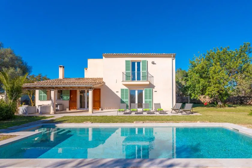 A house and swimming pool are surrounded by trees and lawn.