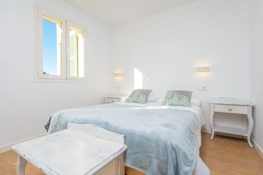 Un dormitorio luminoso con una cama cubierta de ropa de cama azul claro.