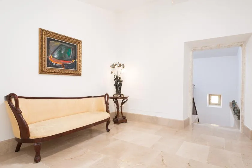 Una luminosa zona de estar con un asiento tapizado de madera y una obra enmarcada.