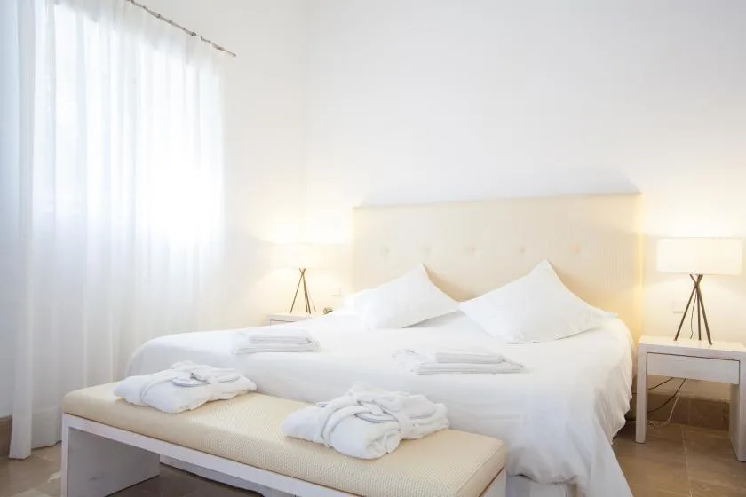 Un dormitorio luminoso con una cama hecha y lámparas de mesilla.