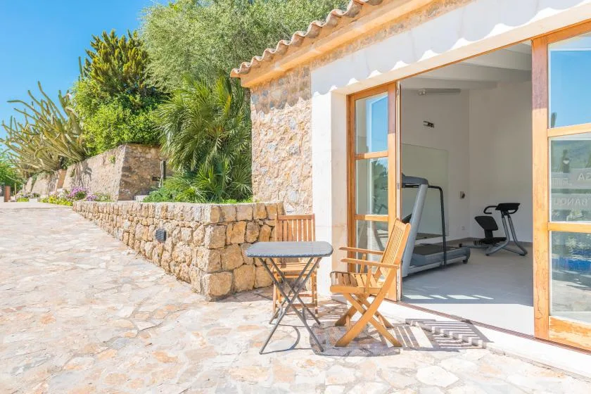 Un pequeño gimnasio se abre a un patio de piedra con asientos al aire libre.