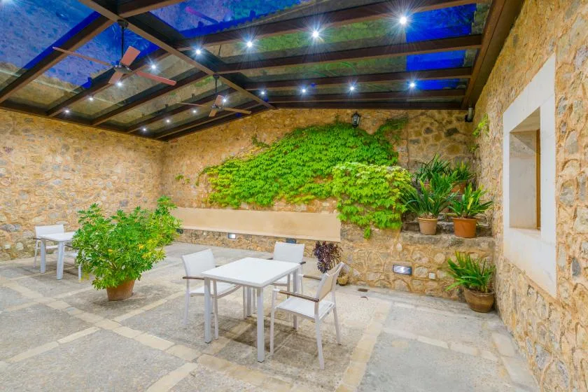 Un patio con paredes de piedra, asientos al aire libre y plantas frondosas.