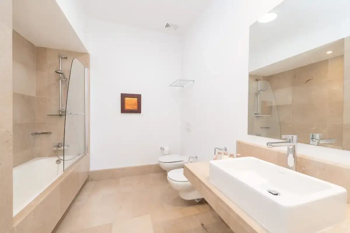Un baño luminoso con bañera, ducha, inodoro y lavabo.