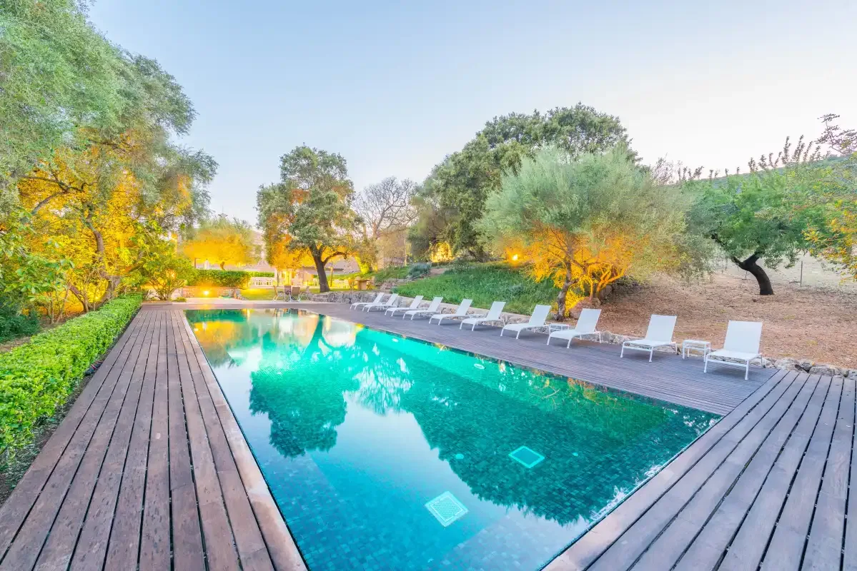 Una piscina al aire libre está rodeada por una terraza de madera y asientos.