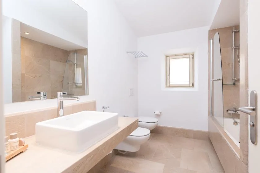 Un baño luminoso con lavabo, inodoro y ducha de cristal.