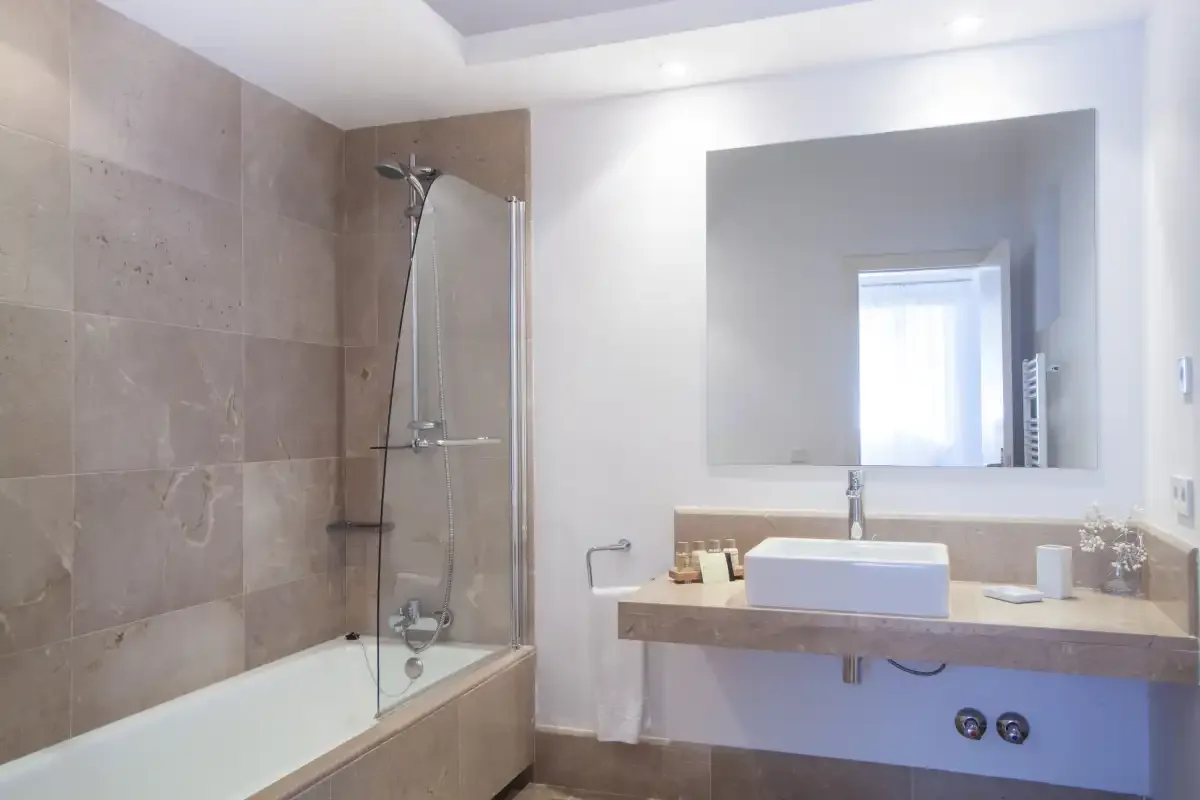 Un baño con bañera y lavabo bajo un espejo grande.