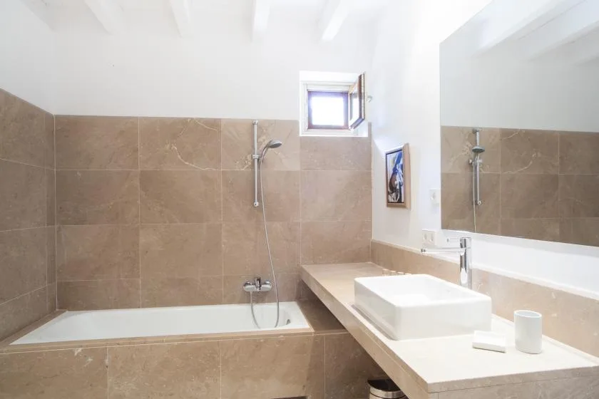 Un baño con bañera y lavabo bajo un espejo grande.