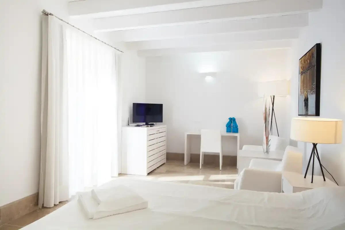Un dormitorio luminoso con una cama, un televisor y una pequeña mesa de comedor.