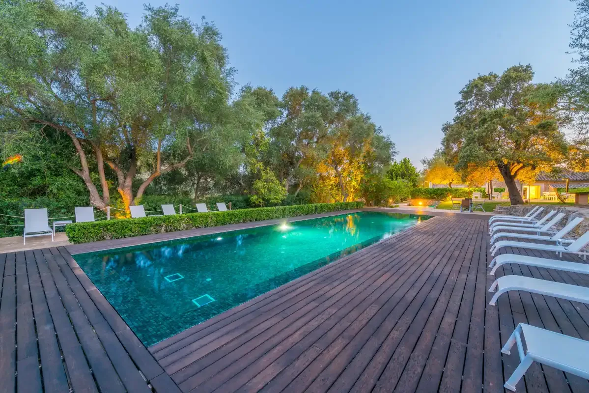 Una piscina al aire libre está rodeada por una terraza de madera y asientos.