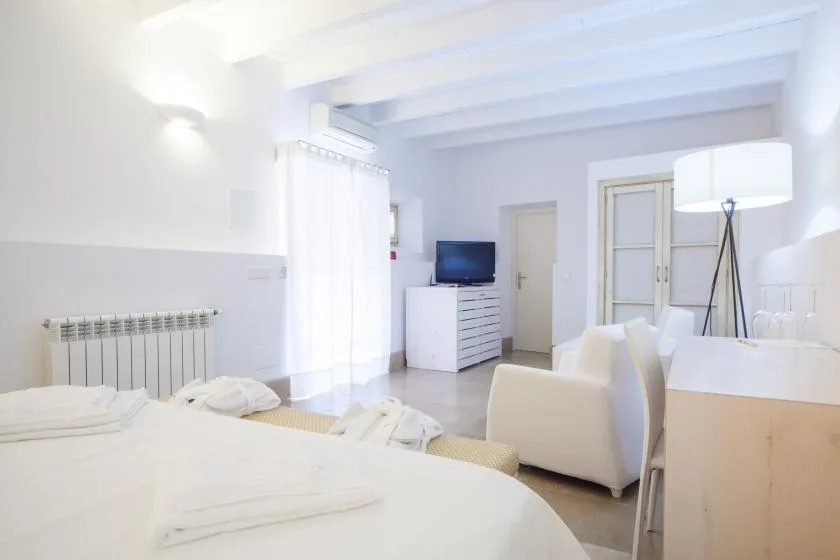Un dormitorio luminoso con una cama, asientos y un televisor.
