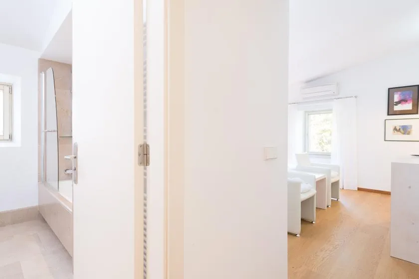 Un dormitorio luminoso con una cama, una ventana y suelo de madera clara.