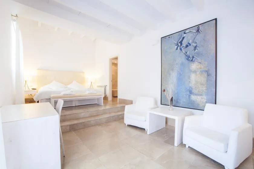 Un dormitorio luminoso con una zona elevada para la cama y asientos blancos.