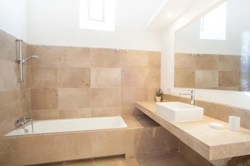 Un baño luminoso con una bañera y un lavabo bajo un espejo grande.