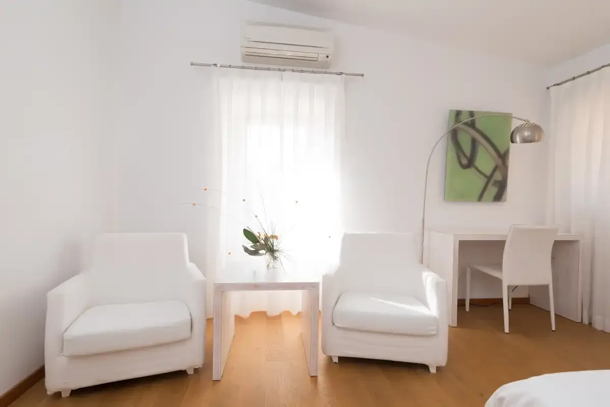 Una luminosa zona de estar con sillones, una mesa pequeña y un escritorio.