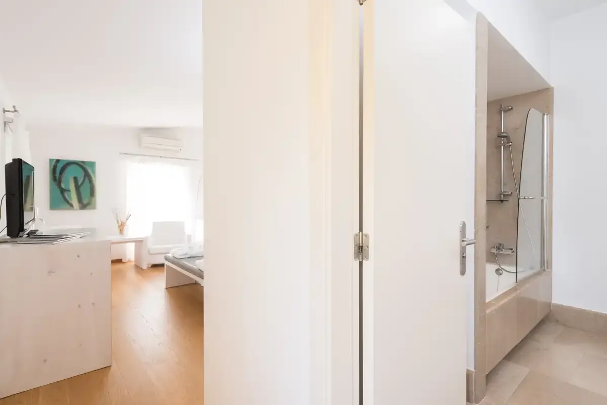 Un dormitorio luminoso con una cama, un televisor y una zona de ducha contigua.