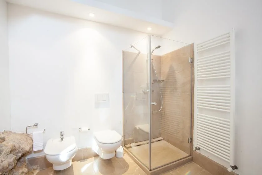 Un baño luminoso con una ducha de vidrio y accesorios blancos.