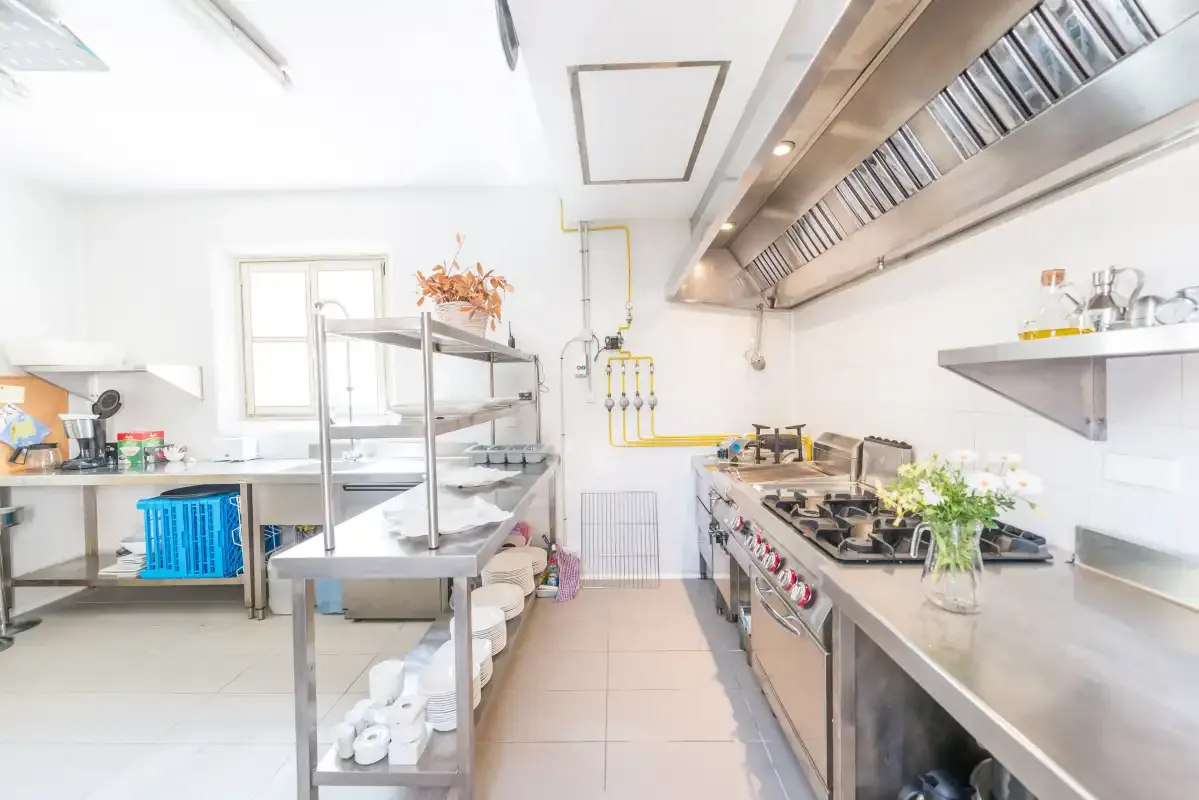 Una cocina comercial luminosa con encimeras de acero inoxidable y equipo de cocina.