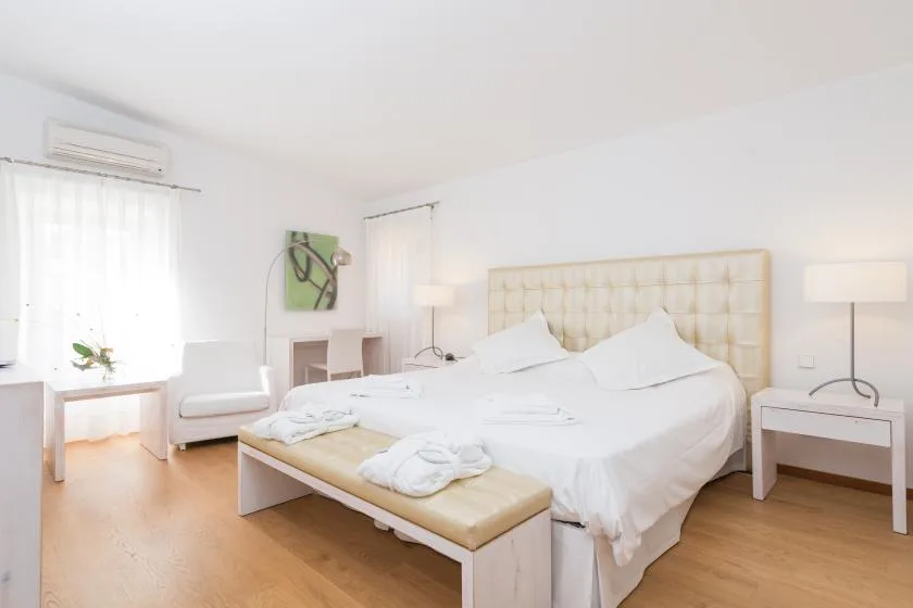 Un dormitorio luminoso con una cama grande y un cabecero tapizado claro.