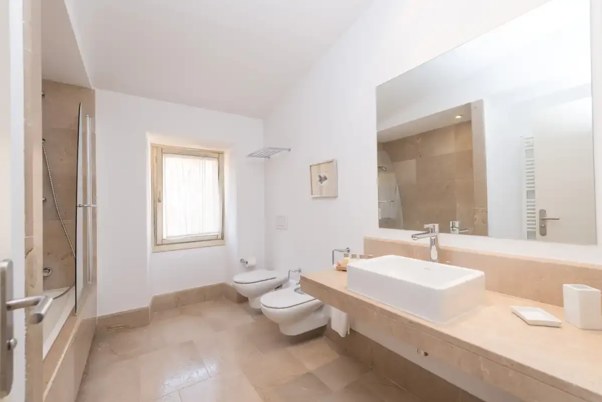 Un baño luminoso con bañera, lavabo suspendido y ventana.