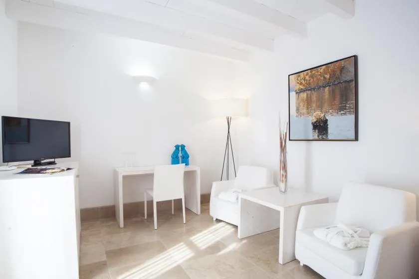 Una sala luminosa con asientos blancos, una mesa de centro y arte en la pared.