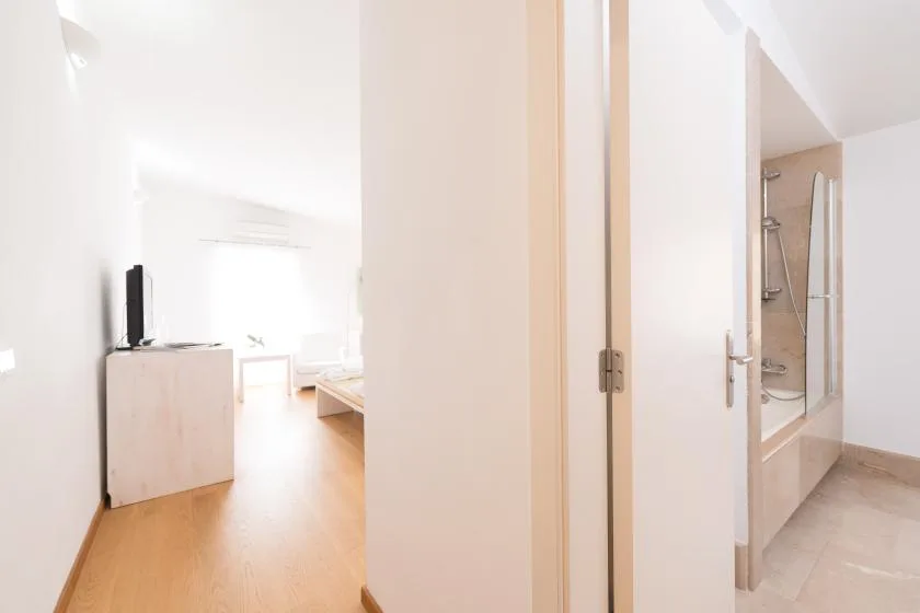 Un pasillo luminoso conecta una zona de dormitorio con un baño.