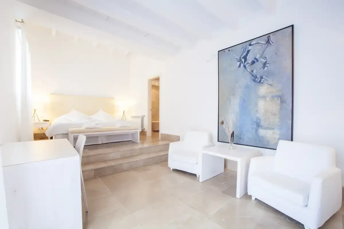 Un dormitorio luminoso con una zona elevada para la cama y asientos blancos.