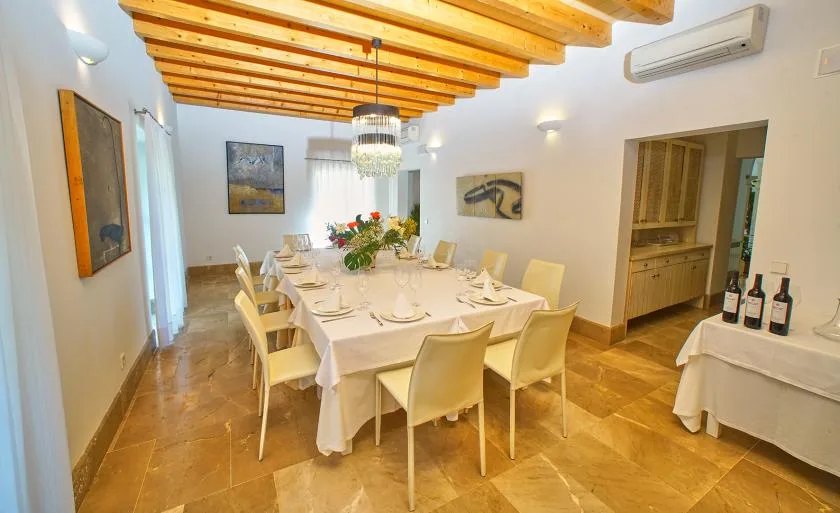 Un comedor con una mesa larga preparada para comer bajo vigas de madera a la vista.