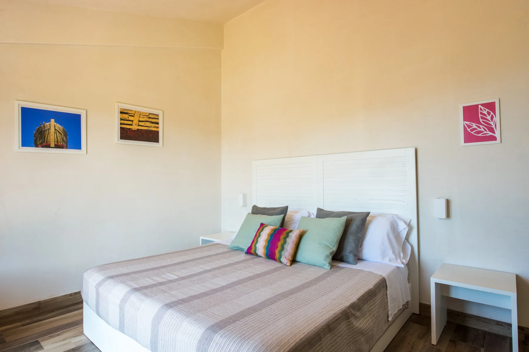 A bedroom with a neatly made bed and colorful accent pillows.
