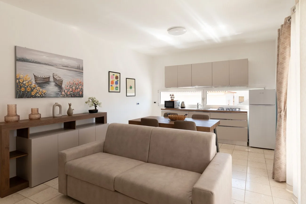 Una sala de estar con un sofá y una cocina abierta al fondo.
