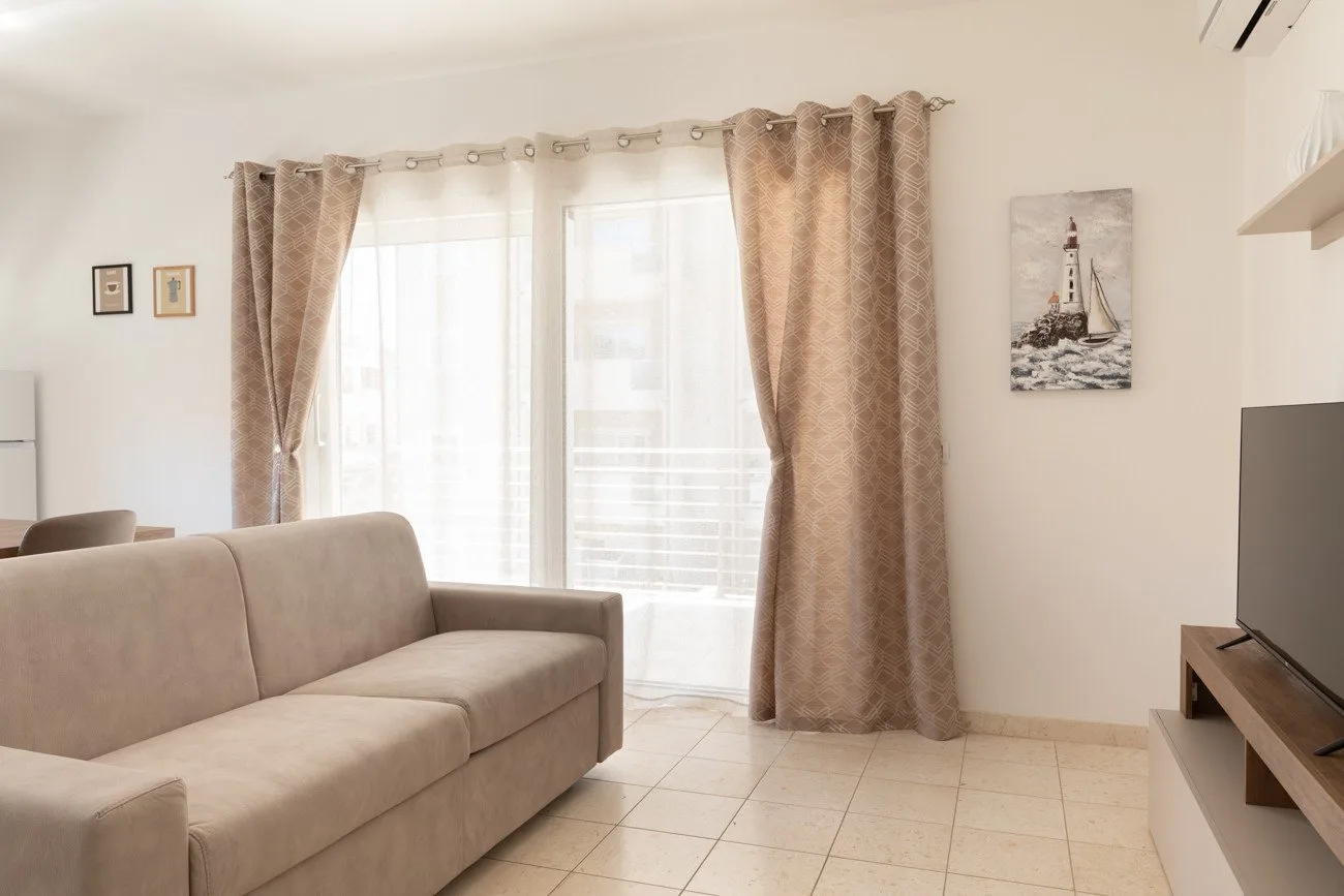Una sala luminosa con asientos junto a una ventana grande con cortinas.