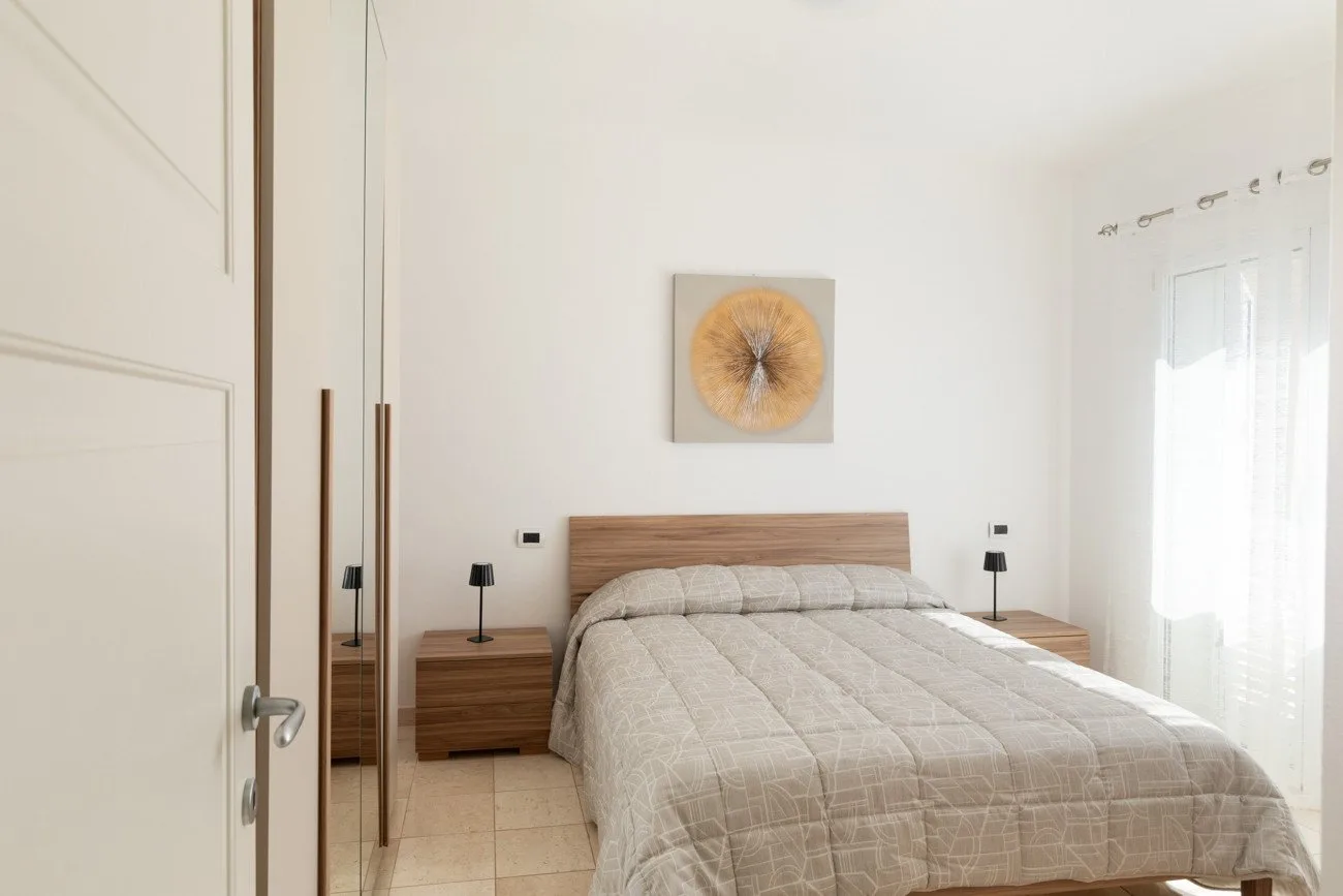 Un dormitorio luminoso con una cama hecha y mesitas de noche a juego.