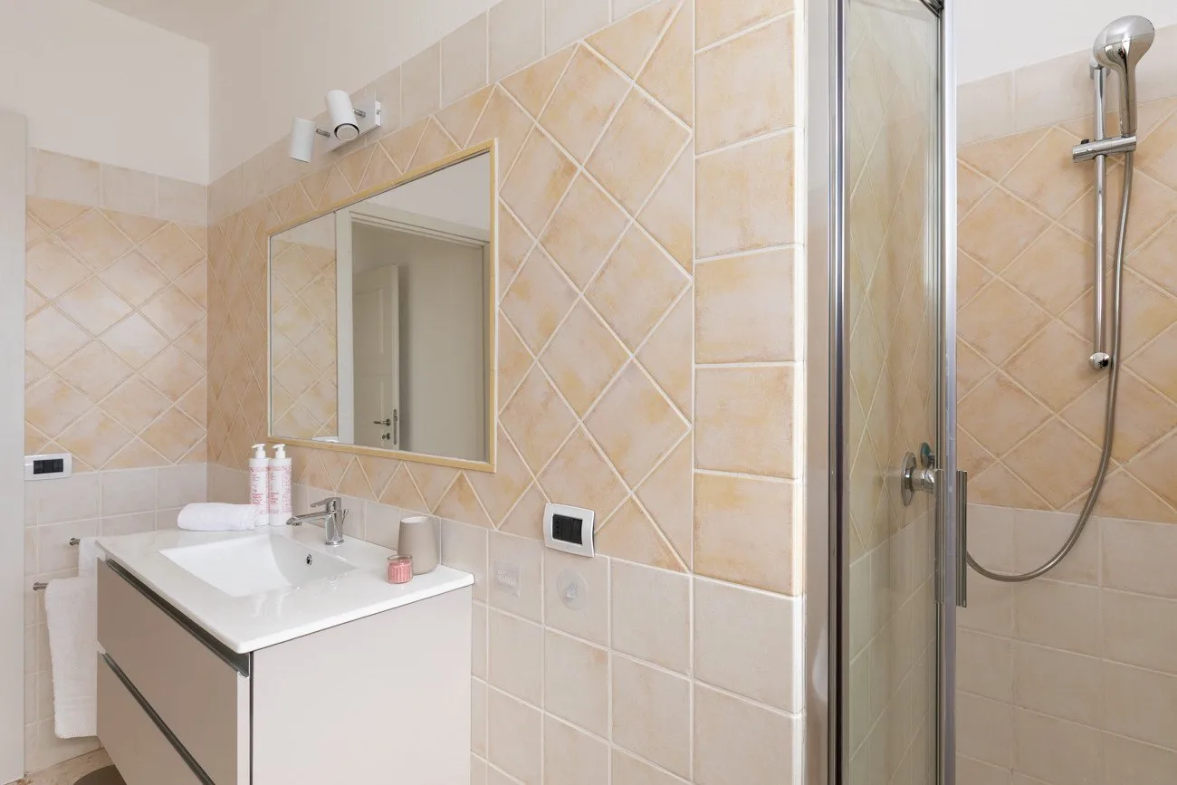 Un baño con azulejos, lavabo, espejo y ducha de cristal.