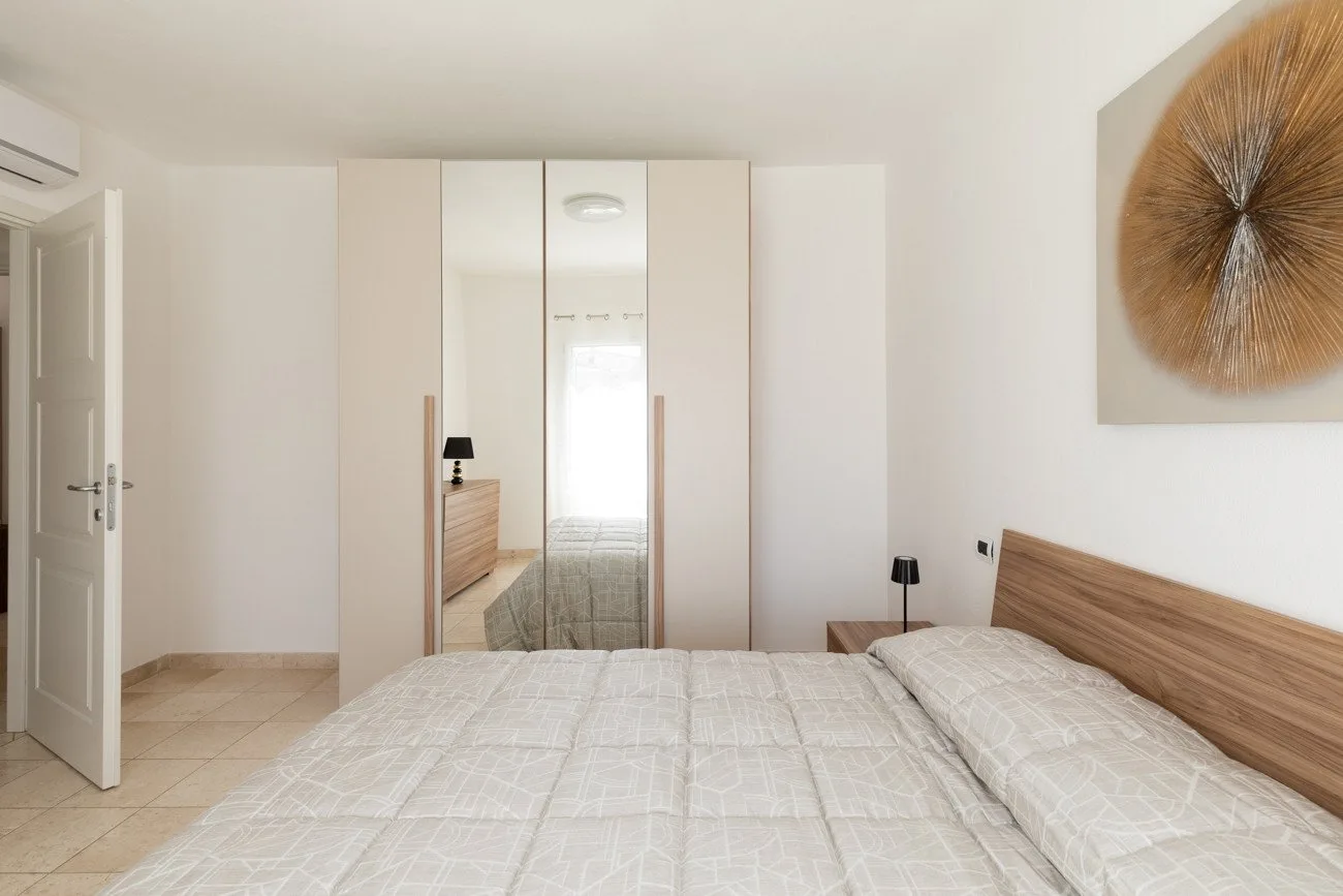Un dormitorio con una cama bien tendida y un armario con espejo.