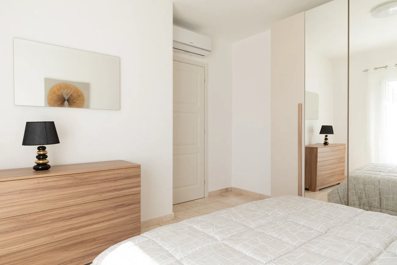 Un dormitorio luminoso con una cómoda de madera y una cama.