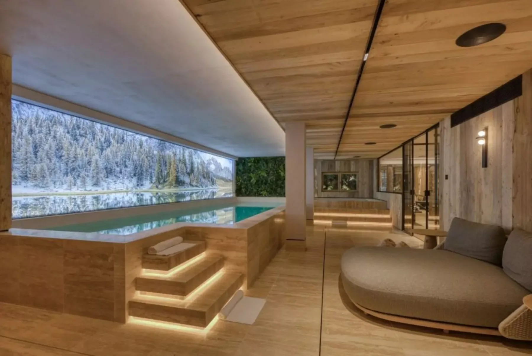 Una zona de piscina cubierta con una ventana larga que da a un paisaje nevado.