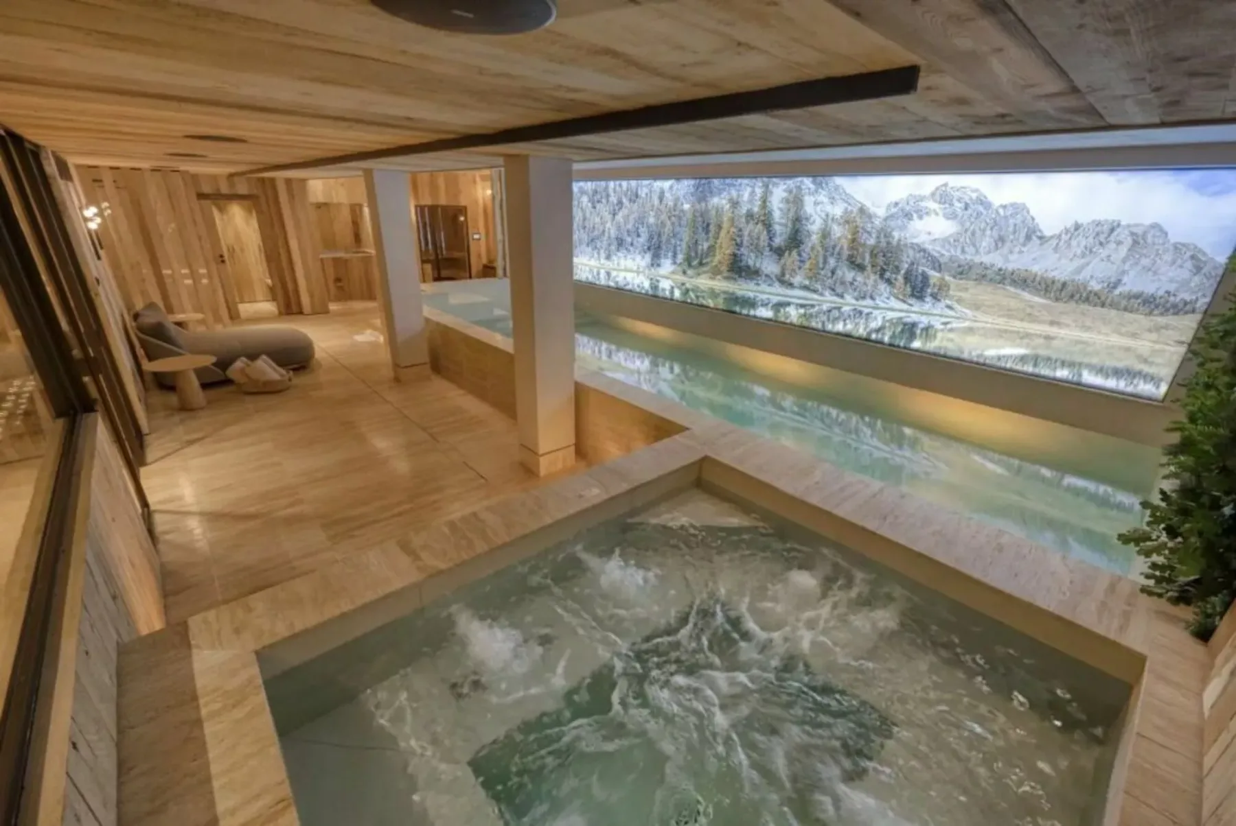 Un spa revestido de madera con una piscina burbujeante y amplias vistas a las montañas.