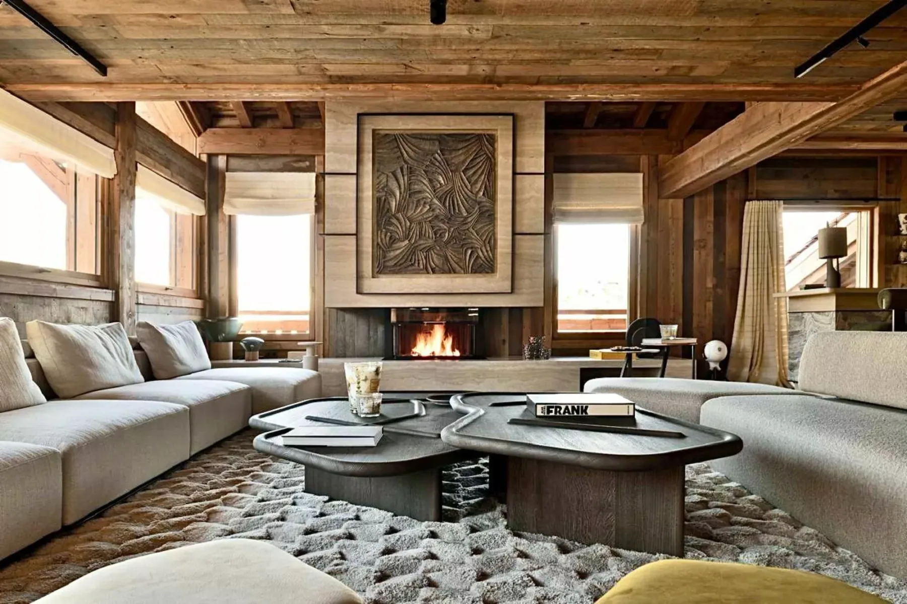 Una sala de estar con paneles de madera, asientos alrededor de una chimenea y mesas bajas.
