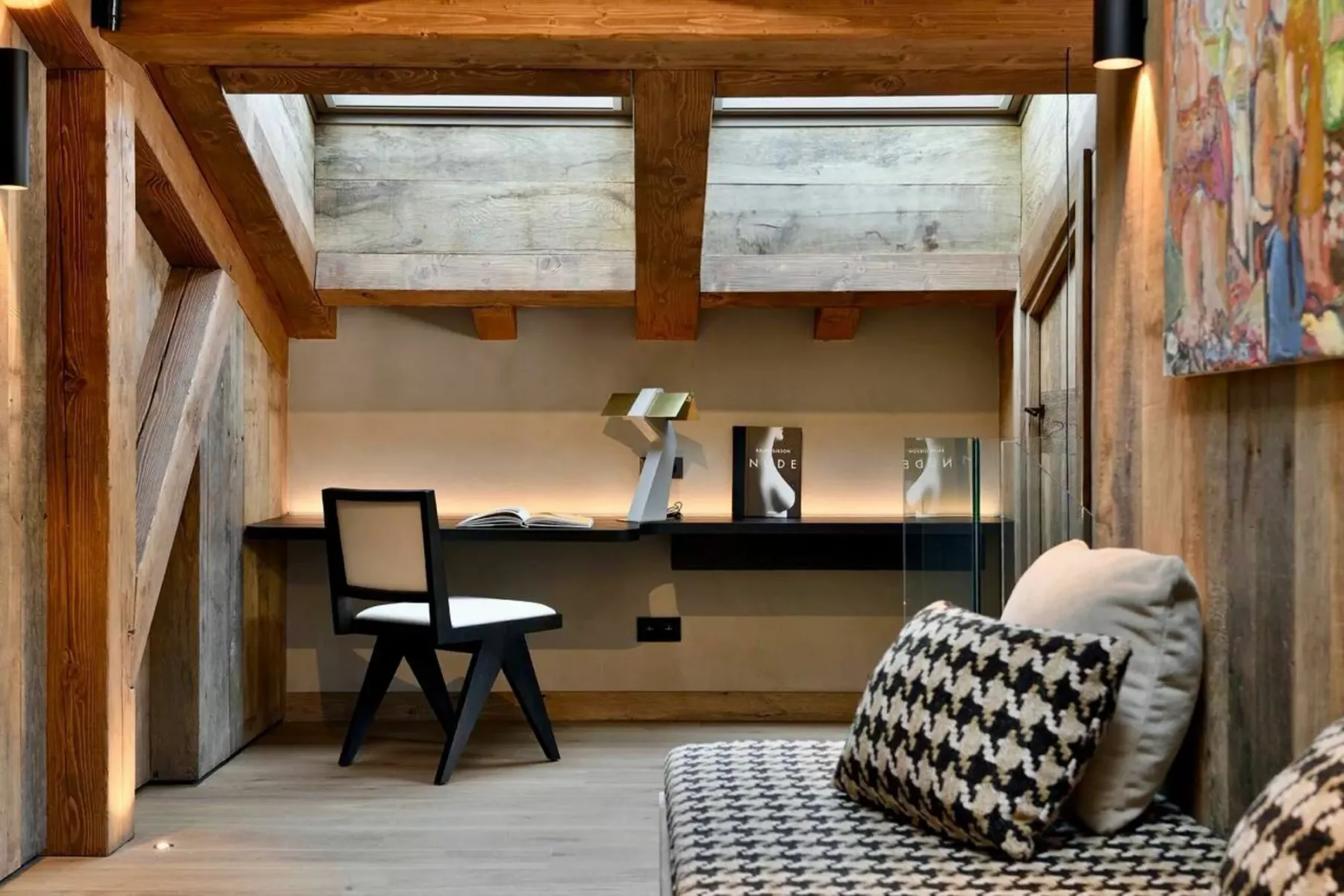 Una zona de estar con escritorio y vigas de madera a la vista.