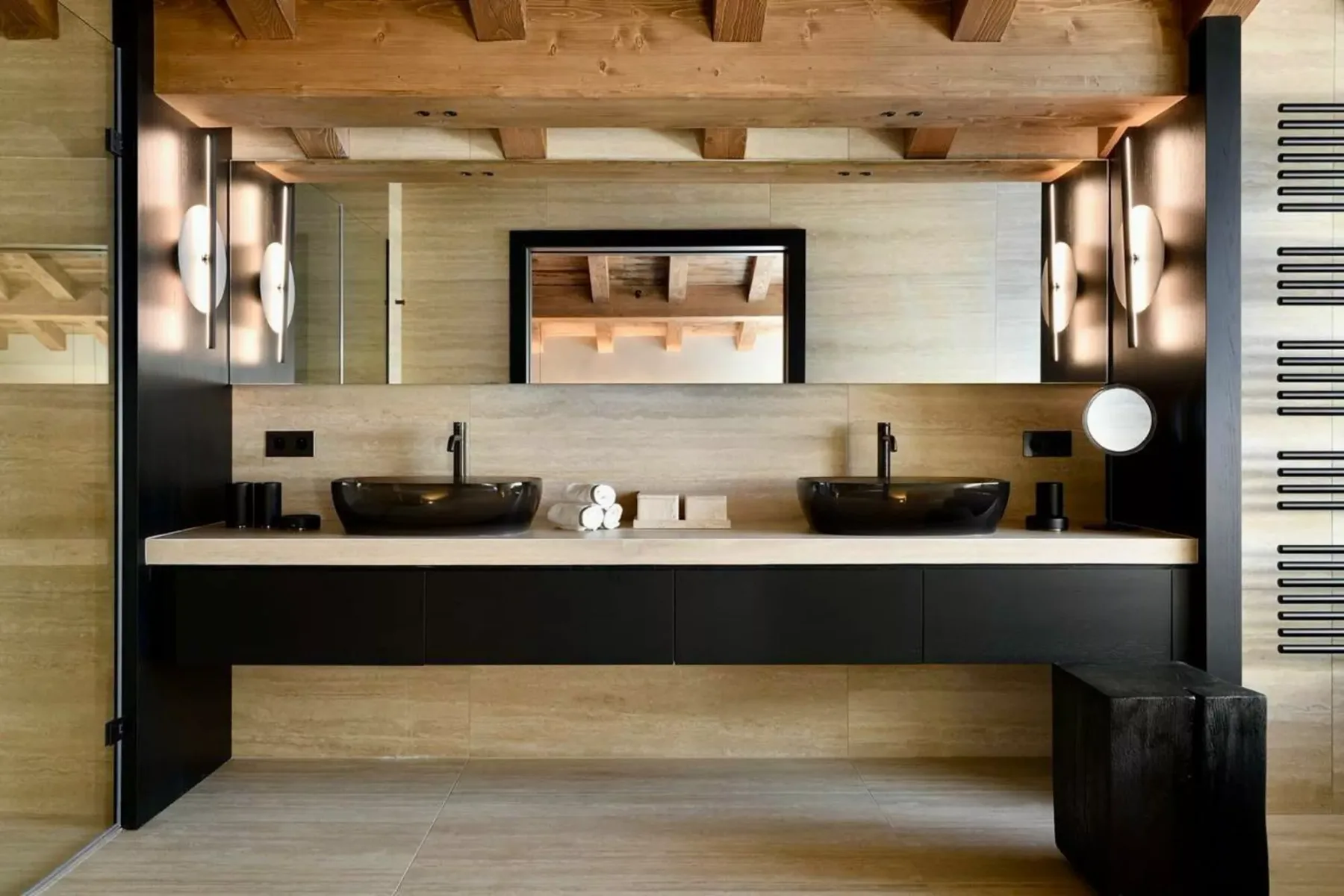 Un lavabo de baño con dos lavabos oscuros sobre encimera y un espejo grande.