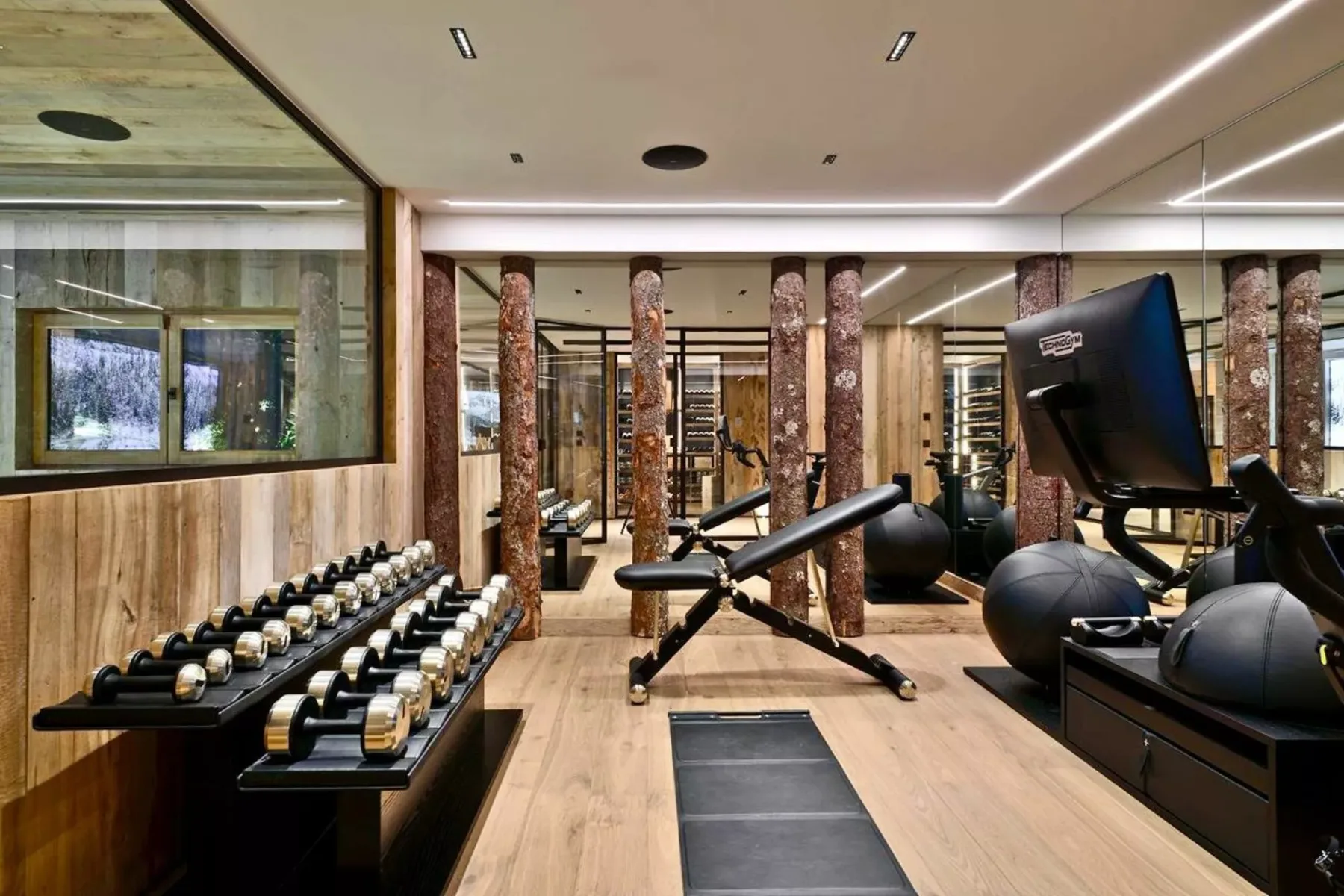 Un gimnasio moderno con estantes de mancuernas, bancos de ejercicio y equipos de entrenamiento.