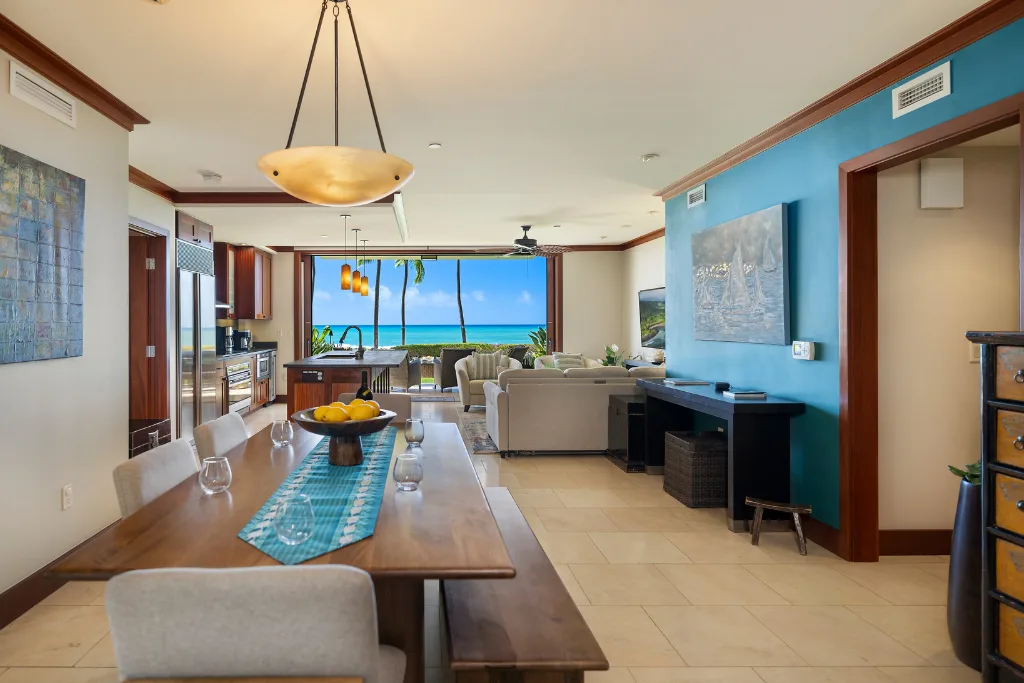 Una luminosa sala-comedor de concepto abierto cuenta con una mesa larga y vistas al mar.