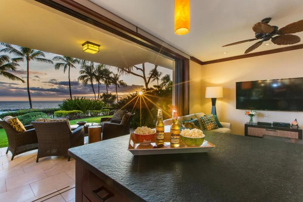 Una sala abierta con asientos y una amplia vista de la playa y las palmeras.